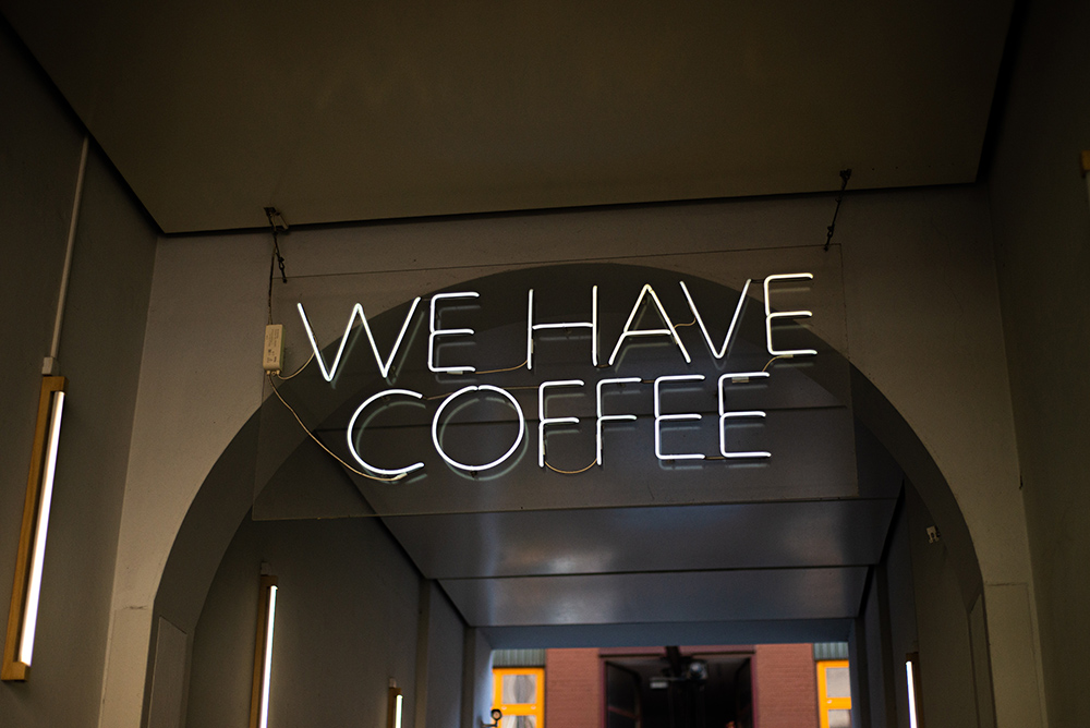 White neon sign reads "WE HAVE COFFEE."